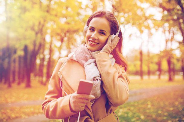 woman with smartphone and earphones in autumn park - Fotoğraf, Görsel