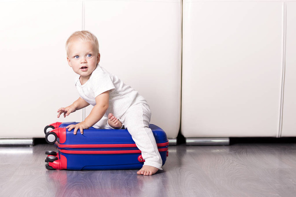Lindo niño sentado en la maleta y mirando a la cámara
 - Foto, imagen