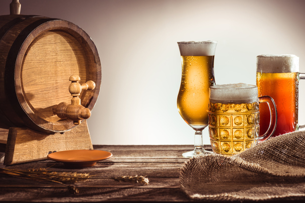 barrel and different beer in glasses - Фото, изображение