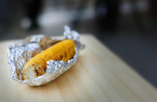 Baked yellow corn in foil on white background - Foto, afbeelding