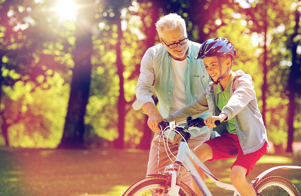 grandfather and boy with bicycle at summer park - Фото, изображение