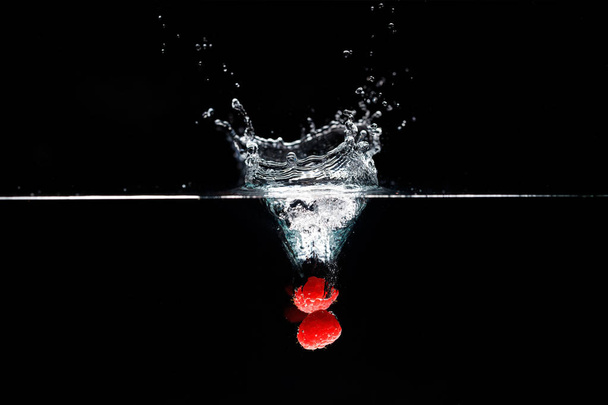 Two raspberrys falls deeply under water with a big splash. - Photo, Image