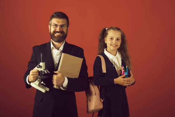 Kid and dad hold microscope, book and stationery - Foto, imagen
