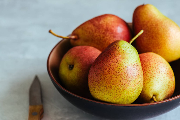 Ripe pears in a plate on a white stone background. Toned.  - Photo, Image