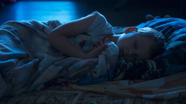 six years old child sleeping in bed at night, the blue moonlight light - Photo, Image
