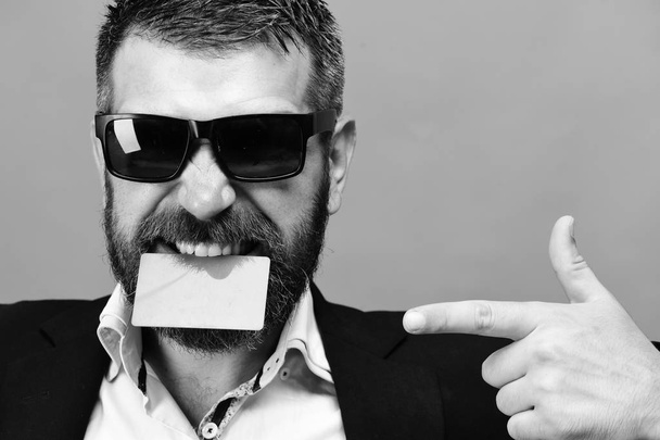 Man with dark beard holds green business card in teeth - Fotografie, Obrázek