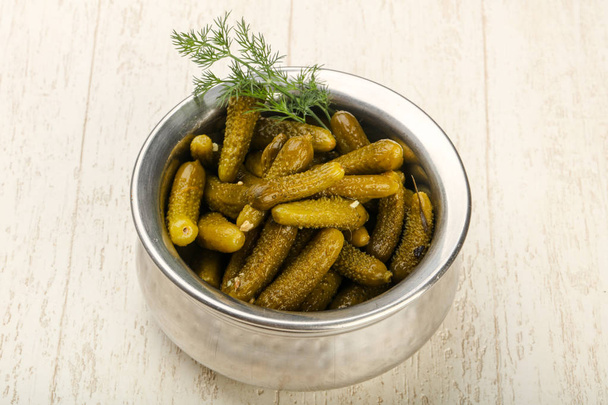 Pickled cucumbers in bowl over wooden background - Photo, Image