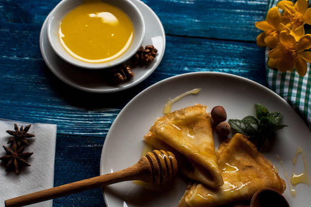 pannenkoeken met honing siroop op een witte plaat. traditionele mousse voor pannenkoek week of stuk. pannenkoeken met geroosterde noten - Foto, afbeelding