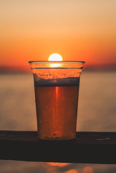 ein Bierbecher mit untergehender Sonne - Foto, Bild