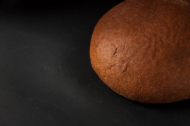 one loaf of bread close-up on a dark background - Zdjęcie, obraz