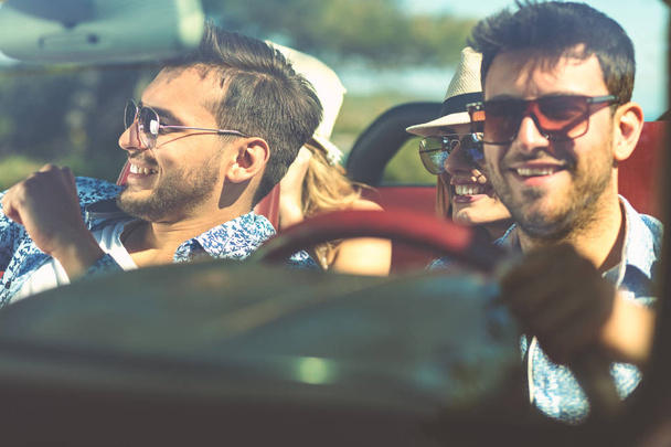 Group of cheerful young friends driving car and smiling in summer - Foto, Imagem