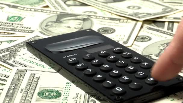 lidská ruka výpočtu na kalkulačce s hromadu dolarové bankovky na pozadí, koncept ekonomiky  - Záběry, video