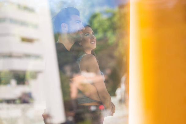 Happy couple behind window cuddling looking away - Фото, зображення