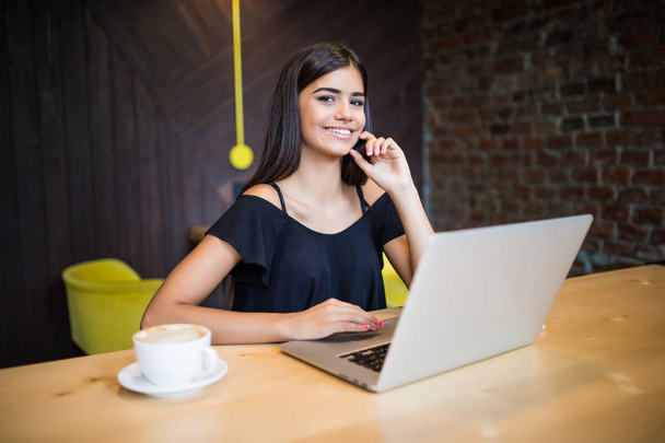 Mooie aantrekkelijke vrouw in het café met een laptop met een koffiepauze - Foto, afbeelding