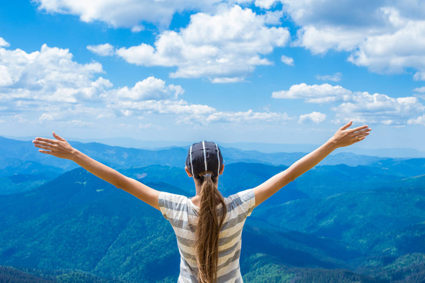 Mujer joven en la cima de la colina levantar la mano con disfrutar y la felicidad. Hermosa vista del cielo en la montaña superior. Concepto de éxito
 - Foto, imagen
