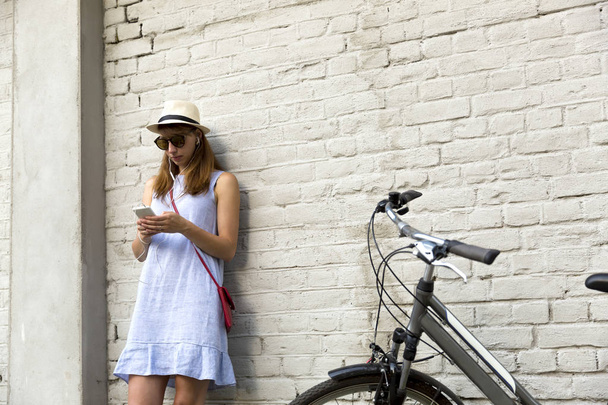Концепция городской жизни. Молодая женщина стоит рядом с белым кирпичом
  - Фото, изображение
