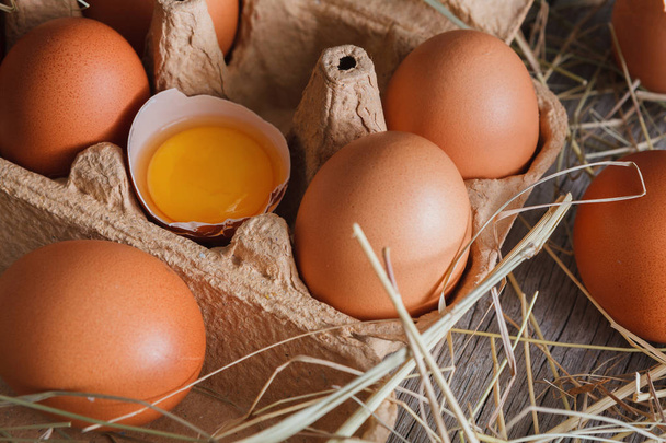 Φρέσκο κοτόπουλο καφέ αυγά σε χαρτοκιβώτιο σε ρουστίκ ξύλινα φόντο - Φωτογραφία, εικόνα