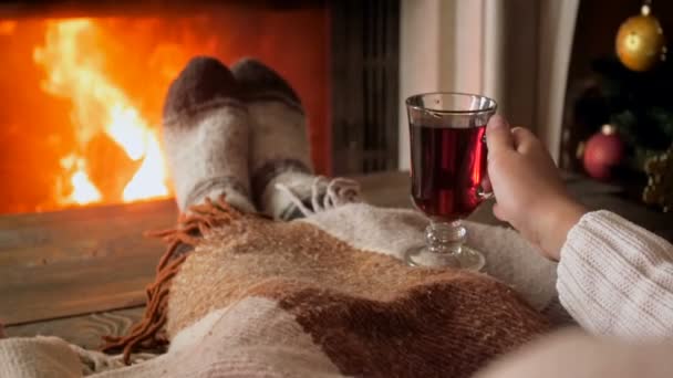 Slow motion footage of woman in wool socks sitting at fireplace and holding cup of hot tea - Footage, Video