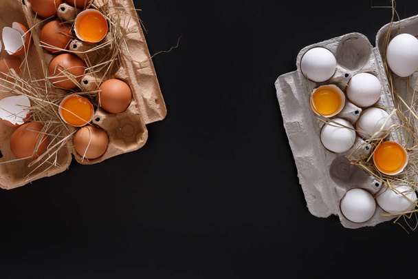 Φρέσκα αυγά καφέ σε κουτί σε μαύρο φόντο - Φωτογραφία, εικόνα