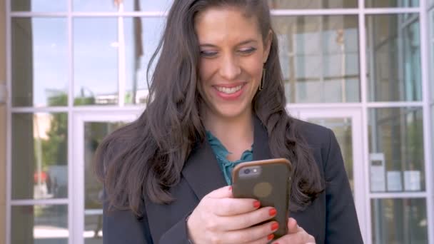 A beautiful happy businesswoman looking up and smiling from her smart phone - Felvétel, videó