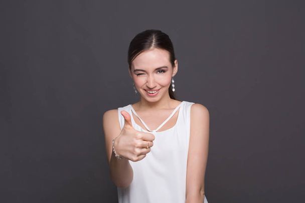 Happy young woman giving thumb up gesture and winking - Φωτογραφία, εικόνα