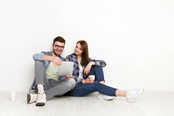 Feliz pareja de compras en línea, sentado en el suelo en casa
 - Foto, Imagen