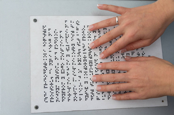 Dłonie dziewczyny czytać tekst napisany w języku Braille'a. Ludzie - Zdjęcie, obraz