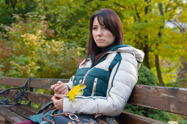 Mujer pensativa con chaqueta sentada en el banco. Gente
 - Foto, imagen