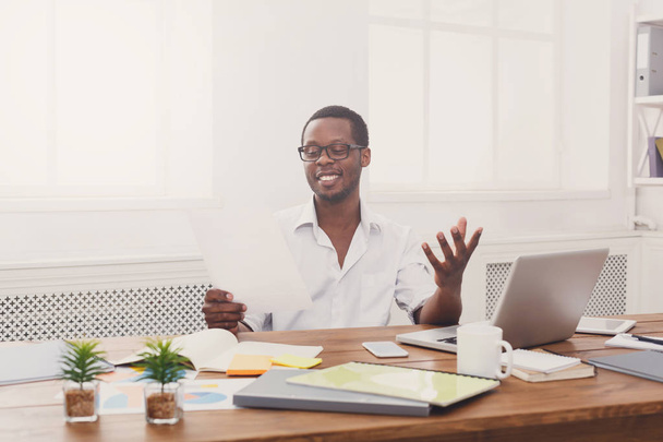 Νέοι μαύρο επιχειρηματίας ανάγνωση εγγράφων σε μοντέρνο λευκό γραφείο - Φωτογραφία, εικόνα