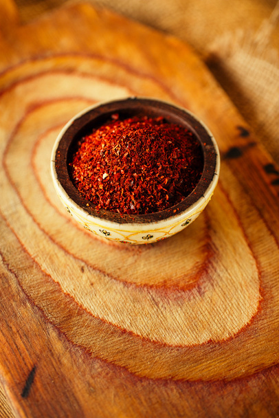 Red hot chilli pepř vločky v misce na dřevěné desce backgro - Fotografie, Obrázek