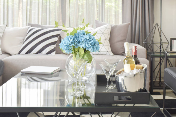 Light blue flower with wine bottles and glasses of wine on the tabla in modern living room - Fotoğraf, Görsel