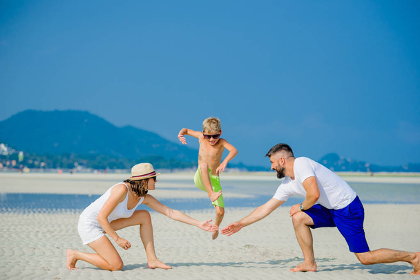 Feliz familia joven de tres divirtiéndose en la playa soleada desierto
 - Foto, Imagen