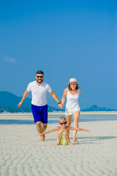 Heureuse jeune famille de trois personnes qui s'amuse sur la plage ensoleillée du désert
 - Photo, image