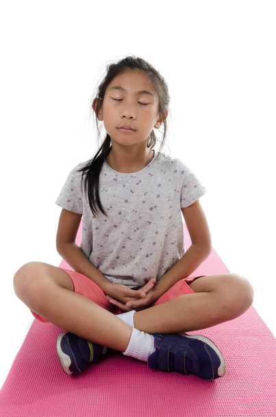 Girl making meditaion on pink yoga mat with white background. - Foto, Imagen