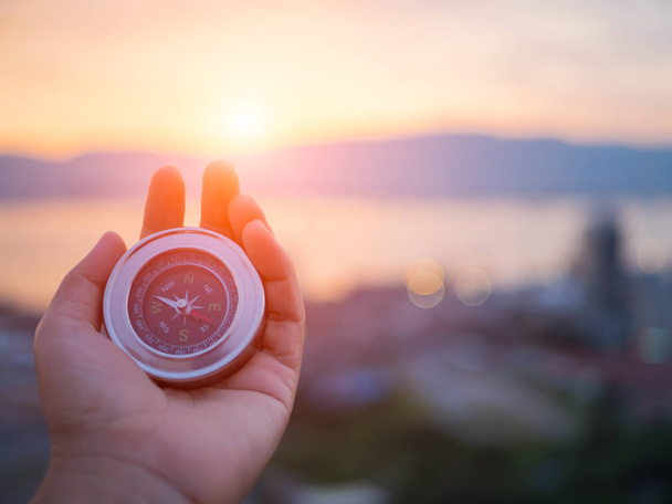 Closeup hand holding compass with  mountain and sunset sky  - Foto, Imagen