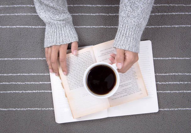 Расслабься женщина рука держа чашку горячего напитка и читать книгу
 - Фото, изображение