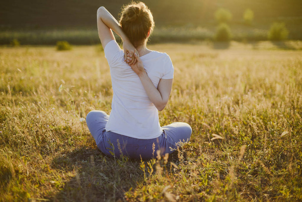 Young woman sits in namaste yoga pose with city on background. F - Zdjęcie, obraz