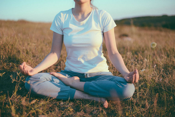 Frau praktiziert Yoga und meditiert in der Lotusposition auf der  - Foto, Bild