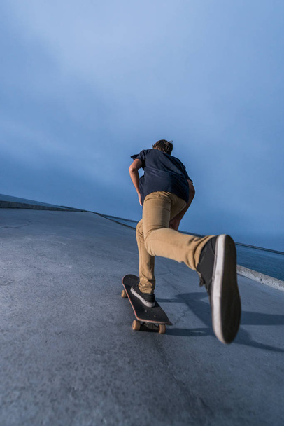 Skateboarder pushing on a concrete pavement - Fotó, kép
