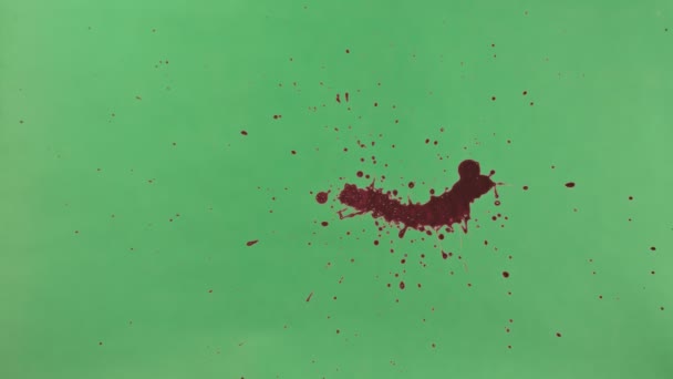 Vörös festék fröccs fölött zöld képernyő háttér - Felvétel, videó