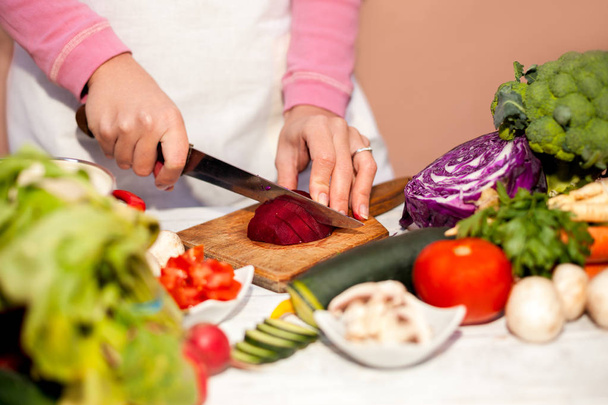 Femme au foyer avec un couteau coupant betterave, coupe de légumes dans le th
 - Photo, image