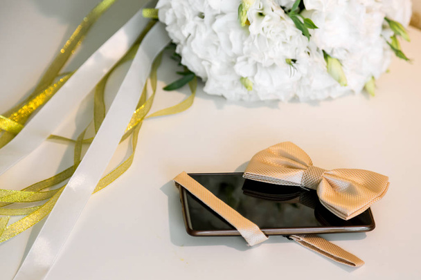 Аксессуары день свадьбы жениха. Мобильный телефон и бабочка
 - Фото, изображение