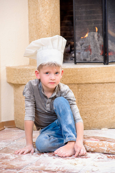 Chlapec v šéfkuchaře klobouky u krbu sedí na kuchyni f - Fotografie, Obrázek