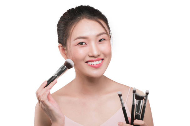 Красивая женщина с косметическими инструментами для макияжа рядом с лицом
. - Фото, изображение