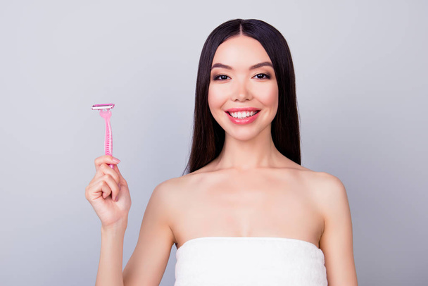 Young cheerful asian girl with pink shaver is standing isolated  - Foto, Bild