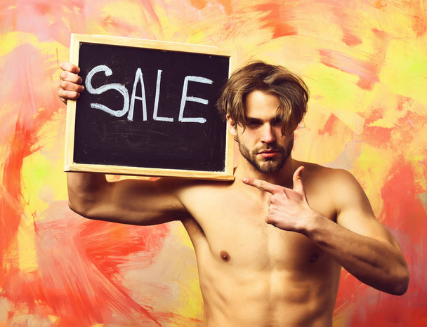 Caucasian bearded sexy macho man holding board with Sale inscrip - Foto, afbeelding
