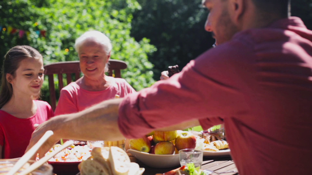 šťastná rodina s večeří nebo letní zahradní party - Záběry, video