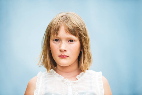 Retrato de cerca de la adorable niña con corte de pelo corto bob de pie sobre fondo azul
 - Foto, Imagen