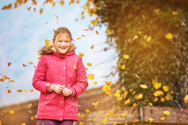 Parlak kırmızı parka ceket sonbahar parkta oynarken komik küçük kız - Fotoğraf, Görsel