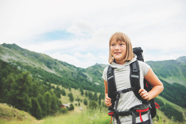 Onnellinen pikkutyttö patikoimassa Sveitsin Alpeilla, mustassa repussaan, matkustamassa lasten kanssa. Kuva otettu kantonissa Valais, Sveitsi
 - Valokuva, kuva